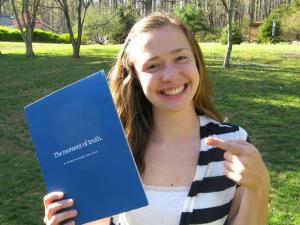 female high school senior holding and pointing to her acceptance packet from Elizabethtown College