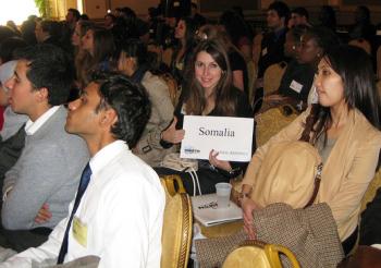 student in crowd at model un conference holding up paper with "somolia" written on it and giving thumns up