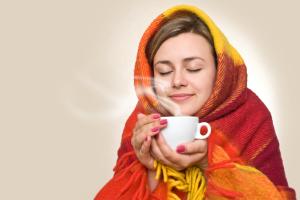 girl wrapped in blanket holding steaming tea cup